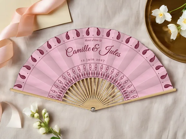 Éventail de mariage personnalisé « Cachemire », gouttes de cachemire le long du bord et rosace autour du centre, toile : rose poudré, impression : bordeaux, posé sur une table de mariage