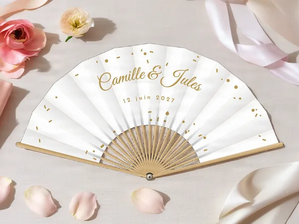 Éventail de mariage personnalisé « Confettis », petits confettis éparpillés autour des prénoms, toile : blanc, impression : or, posé sur une table de mariage