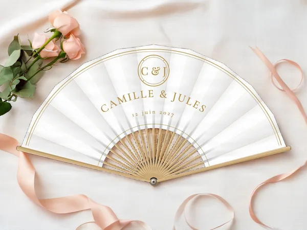 Éventail de mariage personnalisé « Monogramme doré », médaillon à initiales au-dessus des prénoms et double filet au bord, toile : blanc, impression : or, posé sur une table de mariage