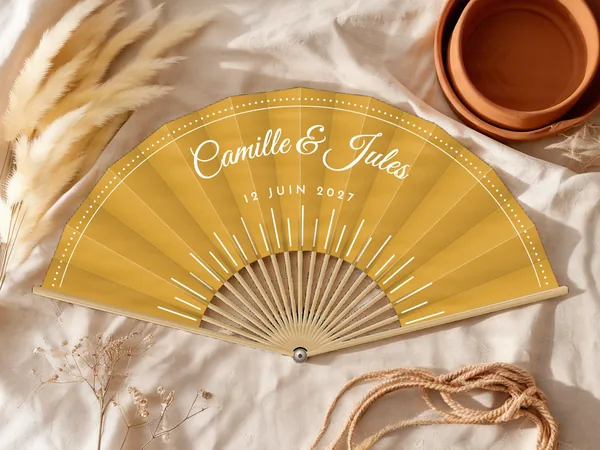 Éventail de mariage personnalisé « Rayons de soleil », rayons fins partant du bas et frise pointillée en bordure, toile : moutarde, impression : blanc, posé sur une table de mariage